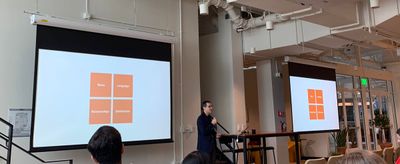 Jorge stands in front of his conclusion slide, a quadrant made up of 4 orange squares with the IA Elements labeled on them.