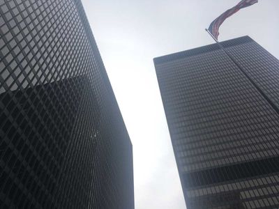 A view of two Chicago buildings and the American flag from below. The buildings' windows are creating very distinct grid lines.