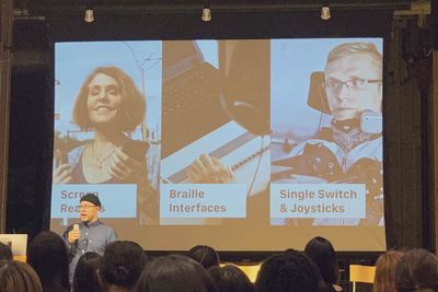 Julian stands in front of his slide, which is a triptych displaying a blind woman using a screenreader, someone sitting at a laptop using a Braille interface, and a man in a wheelchair using a single switch and joystick.